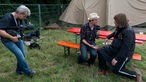 Ebbot Lundberg sitzt mit einem Reporter auf einer Bierbank und wird gefilmt