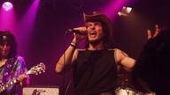 Der Hut tragende Sänger von Victory singt bei Bootleg im April 2006 mit zugekniffenen Augen ins Mikrofon.