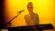 Die Keyboarderin der "Shout Out Louds" sieht konzentriert und angespannt auf ihr Instrument vor sich.