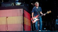 Bassist der Sportfreunde Stiller strahlend auf der Bühne mit seinem Sandberg California Bass in der Farbe Red Worn