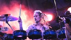 Drummer mit freiem Oberkörper und blonden Rastas beim Schlagzeug  spielen
