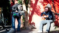 The Inspector Cluzo spielt unplugges unter einem Baum im Biergarten und wird dabei von einem Kameramann gefilmt