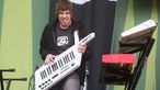 Irie Révoltés Keyboarder Christian „Chriggi“ Comba spielt auf einer portablen Keyboard und wirft dem Fotografen einen diabolischen Blick zu.