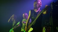 Bassist von John Coffey stimmt seinen Gibson Thunderbird Bass, im Hintergrund gröhlt der Gitarrist etwas ins Publikum