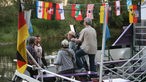 Interviewszene aus der Ferne, am Schiff hängen viele kleine Flaggen von den Bundesländern der BRD