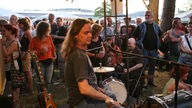 Richard Johnston sitzt hinter seinem Schlagzeug und spielt Unplugged in der Menge mitten im Festivalgelände