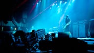Aufnahme der Bühne in blauem Licht mit Sänger darauf und Kamera davor