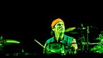 Schlagzeuger spielt auf dem Schlagzeug und wird von grünem Licht angestrahlt