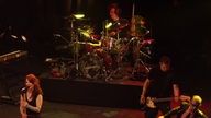 Garbage: Blick auf die Bühne: Links steht eine Sängerin, hinten in der Mitte steht das Schlagzeug und unten rechts die Gitarristen