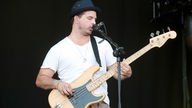 Bassist von Disptach trägt einen Hut und spielt ein H auf seinem Fender Precision Bass und singt ins Mikrofon