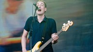 Bassist von Kettcar spielt ein C auf seinem Sandberg California in Gelb und singt etwas traurig daherblickend ins Mikrofon