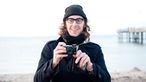 Martin Gretschmann von The Notwist steht mit seiner Kamera am Strand