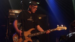 Alias Caylon Bassist mit spielt mit Kappe und Brille bei Bootleg im Oktober 2005