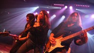 Stacie Collins zwischen den Gitaristen mit Mikrofon in beiden Händen