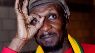 Der Jamaikaner Jimmy Cliff hält vor sein Auge ein mit den Fingern geformtes Loch. Er trägt einen schwarzen bart und eine Reggae-typische Mütze
