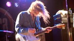 Gitarrist mit fliegenden blonden Haaren im rosa Bühnenlicht