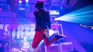 Josh McClorey springt samt Gitarre in die Luft.