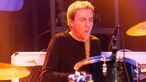 Dave McKay, der Pete MacLeod am Schlagzeug unterstützt, hat den Mund beim Spielen weit geöffnet.