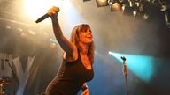 Die Sängerin von Die Happy lacht und streckt ihren rechten Arm, mit dem Mikro in der Hand, beim Underground Festival 2007 weit von sich weg.