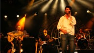 Max Herre rechts im Bild singt, links im Bild sitzen Gitarrist und Bassist vom Freundeskreis beim Underground Festival 2007