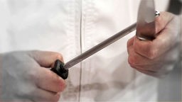 Das Bild zeigt zwei Hände beim Schärfen von einem Messer.
