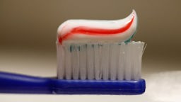 Das Bild zeigt eine blaue Zahnbürste mit etwas Zahncreme.