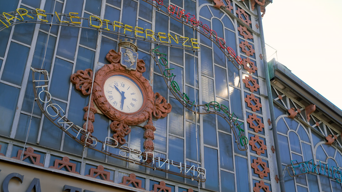 Außenfassade des Turiner Porta Palazzo-Markts mit einer Uhr und verschiedenen Werbe-Schriftzügen.