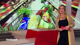 Die Moderatorin im SZ vor dem Bild eines vollen Einkaufswagen im Supermarkt