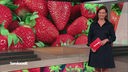 Die Moderatorin im SZ Studio vor einem Bild von Erdbeeren