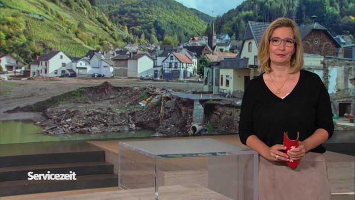 Die Moderatorin im SZ-Studio vor einem Bild von einer Stadt nach der Flutkatastrophe ihm Ahrtal