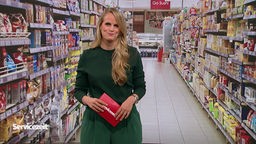 Die Moderatorin steht vor einem Bild vom Supermarkt