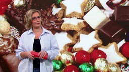 Moderatorin Yvonne Willicks steht im Fernsehstudio. Im Hintergrund ist ein Bild von Weihnachtsplätzchen zu sehen.