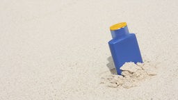 Das Bild zeigt eine Flasche Sonnencreme im Sand.