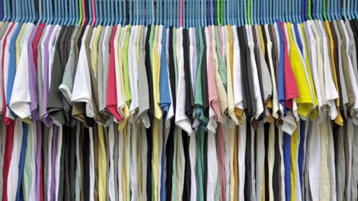 Das  Bild zeigt mehrere T-Shirts an einer Kleiderstange. 