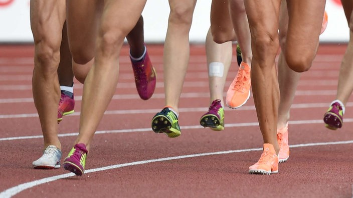 Füße von Läuferinnen auf Laufbahn