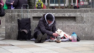 Ein Obdachloser sitzt auf dem Boden mit seinem Hund 
