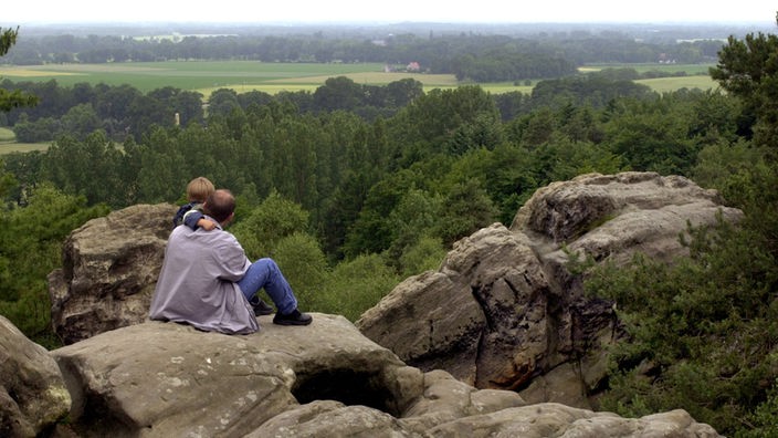 Ein Vater sitzt mit seinem kleinen Sohn auf den "Dörenther Klippen" im Teuteburger Wald.