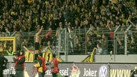 Ein Spieler von Aleminia Aachen ist auf den Zaun des alten Tivoli geklettert und feiert mit Fans