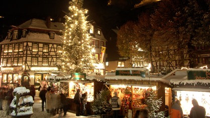 Zwischen Fachwerkhäusern stehen Buden und ein großer Weihnachtsbaum