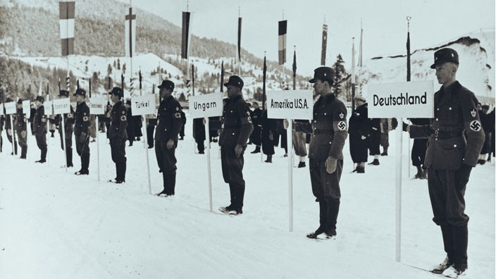 sw-Foto zeigt Soldaten in NS-Uniform in einem verschneiten Stadion, sie halten Schilder mit Ländernamen in der Hand