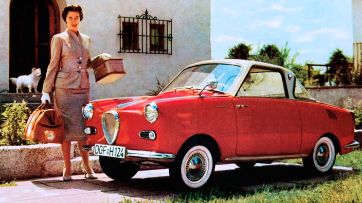 Eine Frau steht vor dem Haus an einem Goggomobil - Werbefoto aus den 1950er Jahren