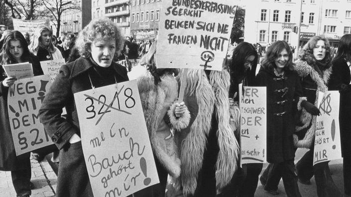 Frauen demonstrieren gegen den §218 mit Schildern, auf denen beispielsweise "Mein Bauch gehört mir" steht