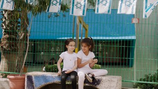 Zwei Mädchen sitzen auf einer Bank an einer Grundschule in Petach Tikva