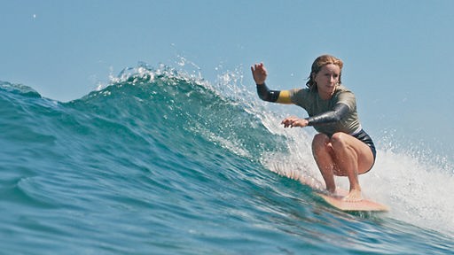 Eine junge Surferin reitet eine Welle