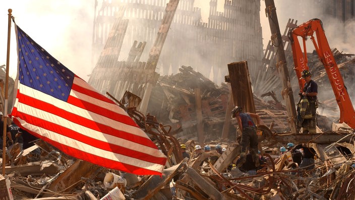 Die US-amerikanische Flagge weht vor den Trümmern des World Trade Centers.