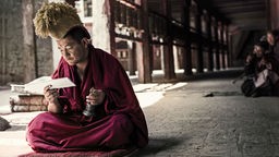 Ein Mönch des Gelbmützen-Ordens im Kloster Samye murmelt in den frühen Morgenstunden sein Mantra.