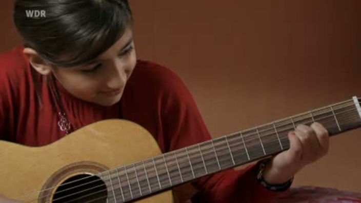 Eine Grundschülerin lernt Gitarre