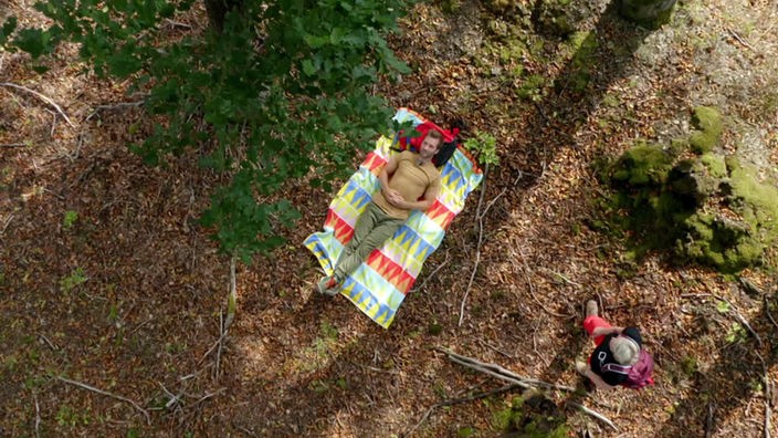 Blick von oben auf  Daniel Aßmann, der auf einer Decke auf dem Waldboden liegt