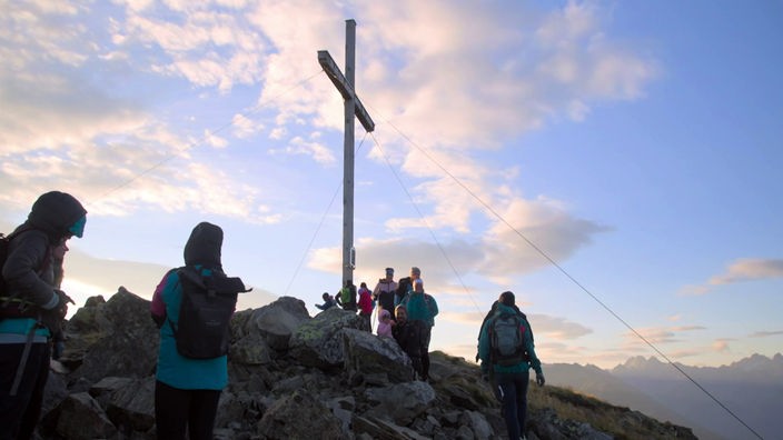 Bergwanderer rund um das Gipfelkreuz auf der Glanderspitze