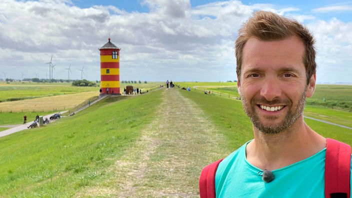 Daniel Aßmann steht vor dem Pilsumer Leuchtturm